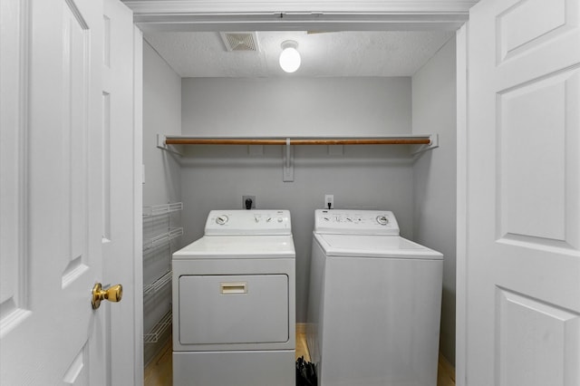 laundry room featuring washing machine and dryer and a textured ceiling