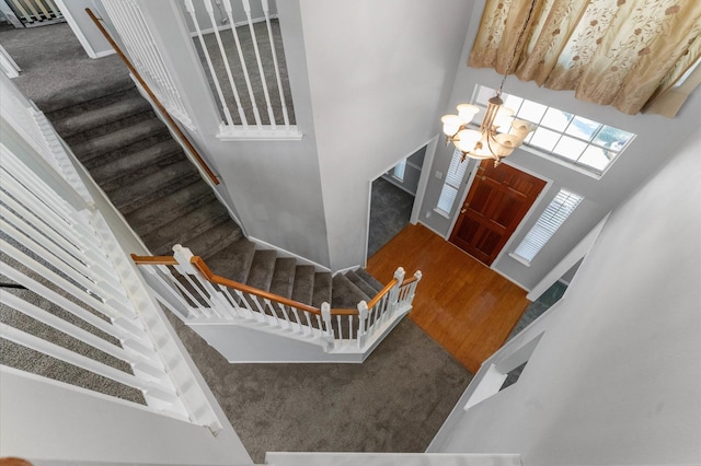 foyer entrance featuring carpet, a towering ceiling, and an inviting chandelier