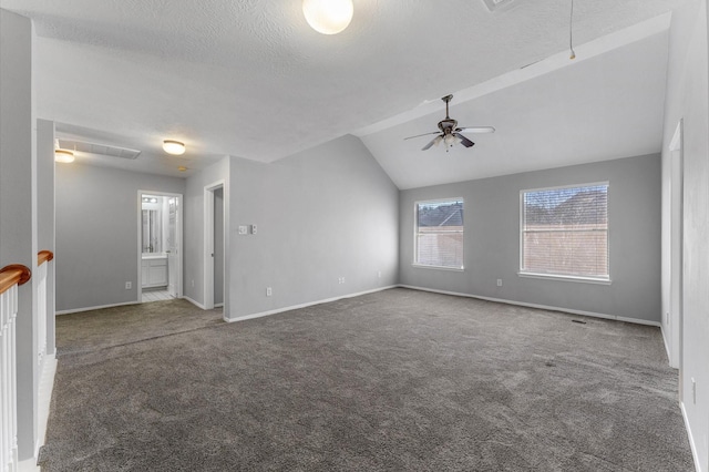 spare room featuring ceiling fan, vaulted ceiling, a textured ceiling, and dark colored carpet