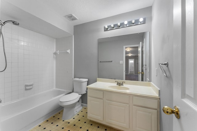 full bathroom featuring vanity, tiled shower / bath combo, toilet, and a textured ceiling