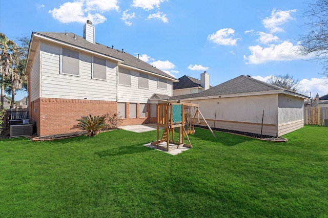 back of property featuring a yard, central AC, and a playground