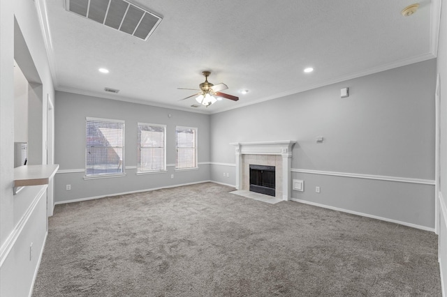 unfurnished living room featuring a tile fireplace, ceiling fan, carpet flooring, ornamental molding, and a textured ceiling