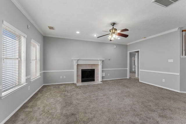 unfurnished living room with a tiled fireplace, carpet floors, ornamental molding, and ceiling fan