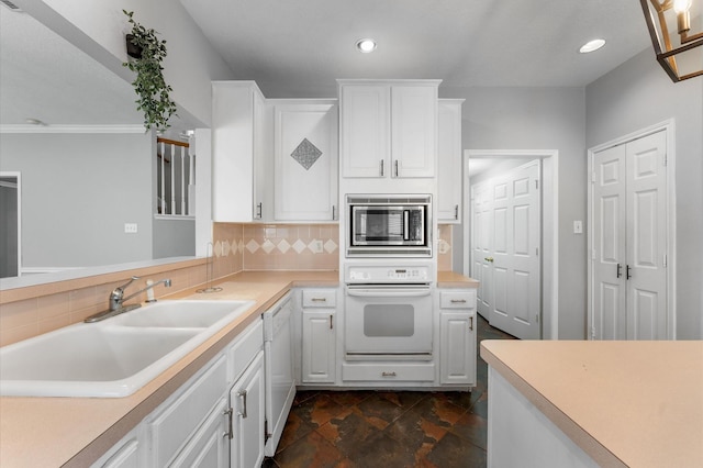 kitchen with white cabinetry, white appliances, sink, and tasteful backsplash