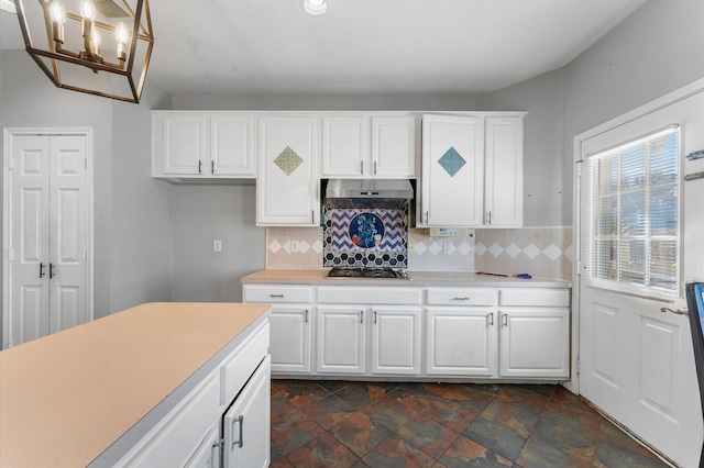 kitchen featuring backsplash, range hood, gas stovetop, and white cabinets