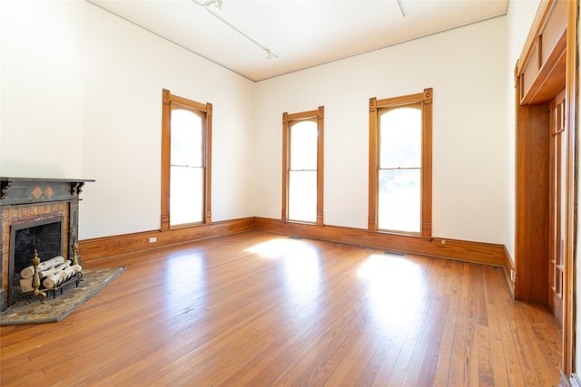 unfurnished living room with a tiled fireplace and light wood-type flooring