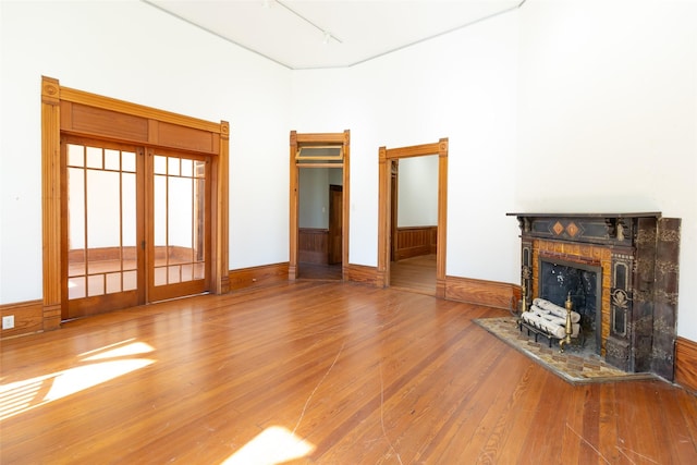 unfurnished living room with track lighting, hardwood / wood-style floors, and a towering ceiling