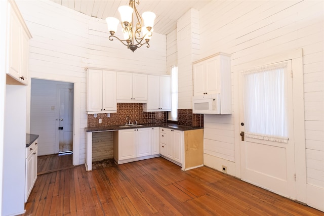 kitchen featuring decorative light fixtures, white cabinetry, sink, backsplash, and dark wood-type flooring