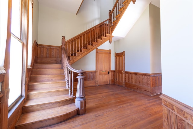 stairway with a towering ceiling and hardwood / wood-style floors