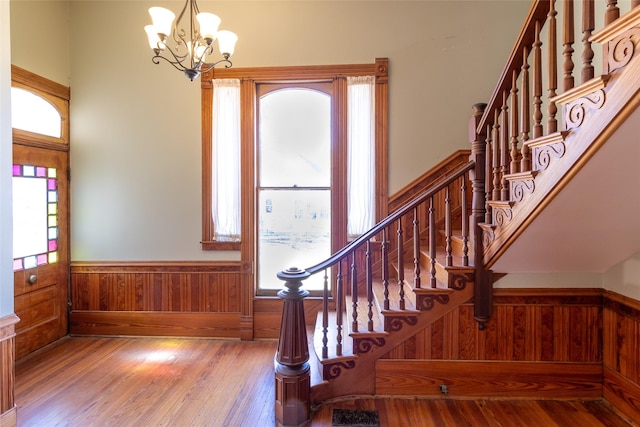 foyer with hardwood / wood-style flooring, plenty of natural light, a notable chandelier, and wood walls