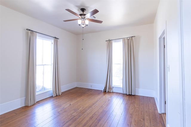 unfurnished room featuring ceiling fan, a wealth of natural light, and light wood-type flooring