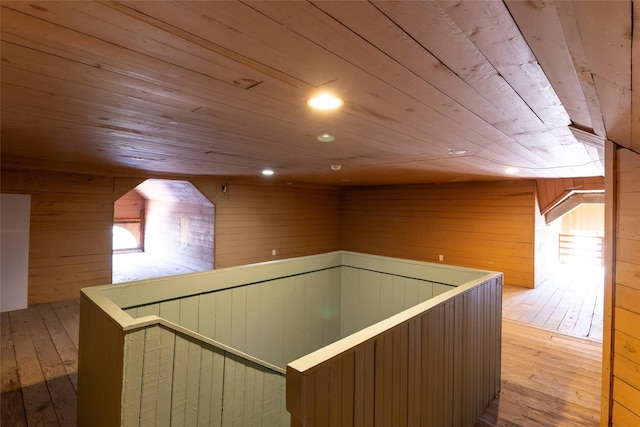 hallway with wooden ceiling, light hardwood / wood-style flooring, and wood walls