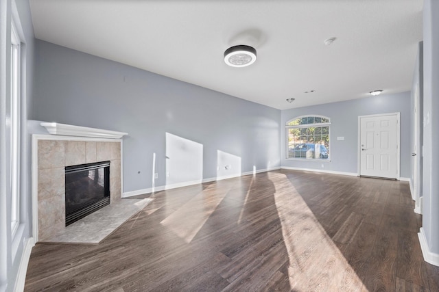 unfurnished living room featuring a tiled fireplace and dark hardwood / wood-style flooring