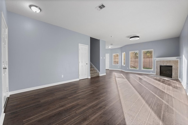 unfurnished living room featuring a tiled fireplace and dark hardwood / wood-style floors