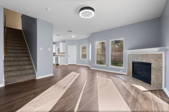 unfurnished living room featuring a tiled fireplace and dark wood-type flooring