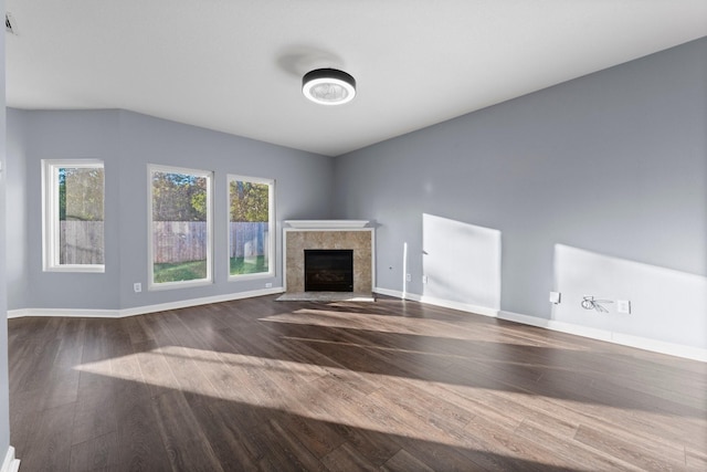 unfurnished living room featuring dark hardwood / wood-style floors and a tiled fireplace