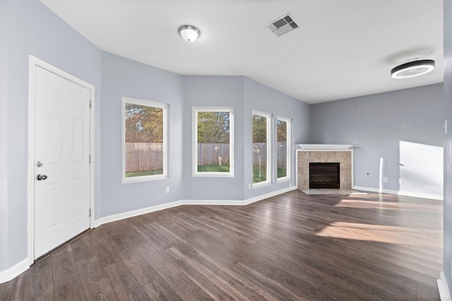 unfurnished living room with plenty of natural light, a fireplace, and dark hardwood / wood-style flooring