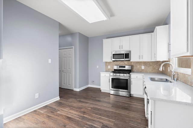 kitchen with sink, white cabinetry, stainless steel appliances, tasteful backsplash, and light stone countertops