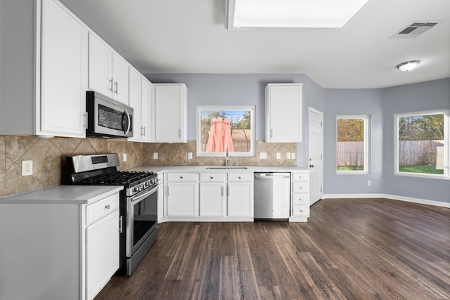 kitchen with sink, white cabinets, backsplash, stainless steel appliances, and dark wood-type flooring