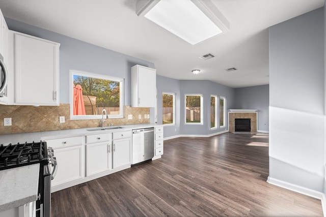 kitchen featuring sink, appliances with stainless steel finishes, white cabinetry, tasteful backsplash, and a tiled fireplace