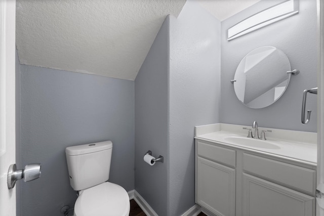 bathroom with lofted ceiling, toilet, a textured ceiling, and vanity