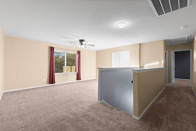 carpeted spare room featuring ceiling fan and a textured ceiling