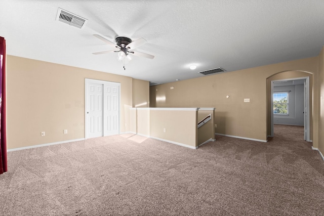 carpeted empty room featuring ceiling fan and a textured ceiling