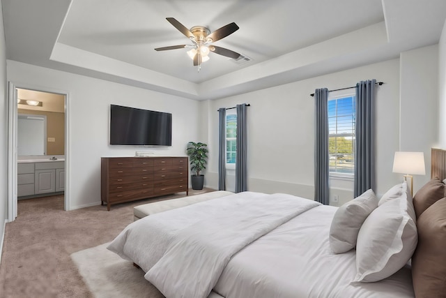 bedroom with a raised ceiling, light carpet, and multiple windows