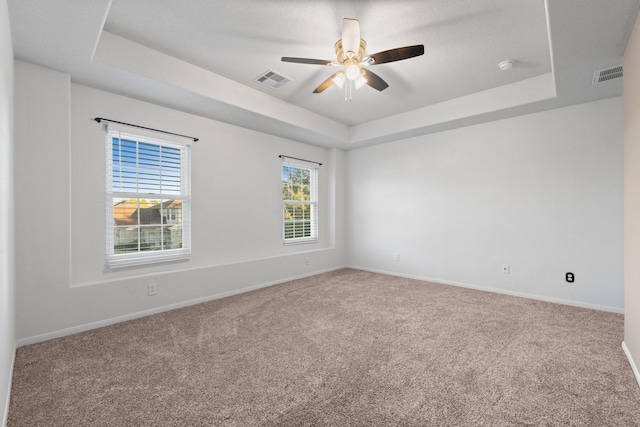 unfurnished room with ceiling fan, a raised ceiling, and carpet