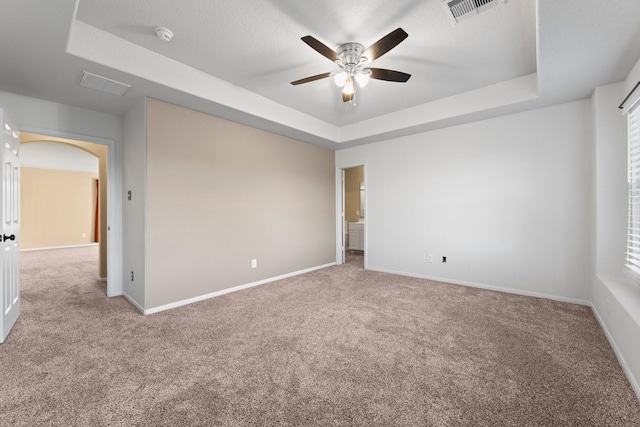 unfurnished room featuring light colored carpet, a raised ceiling, and ceiling fan