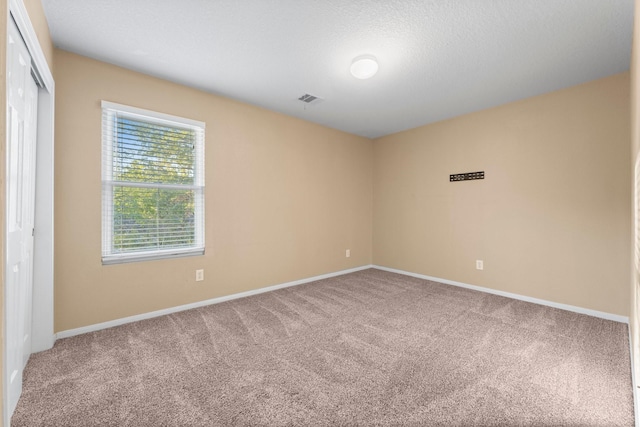 carpeted spare room with a textured ceiling