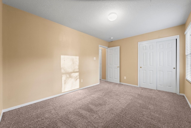 unfurnished bedroom featuring multiple windows, carpet, a textured ceiling, and a closet