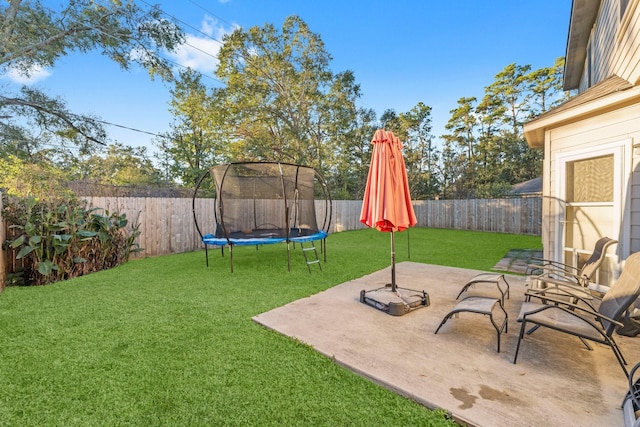 view of yard featuring a trampoline and a patio