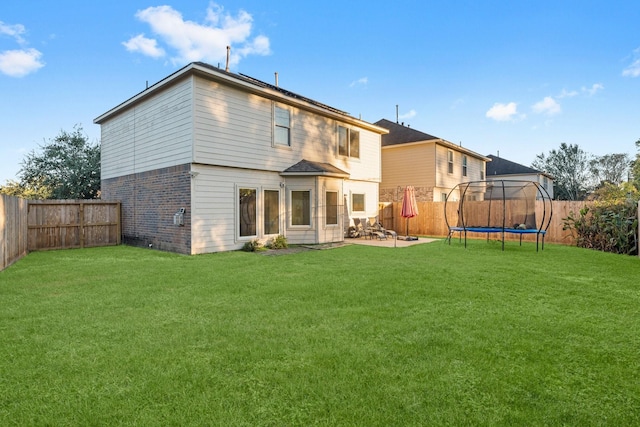 back of house featuring a trampoline, a yard, and a patio