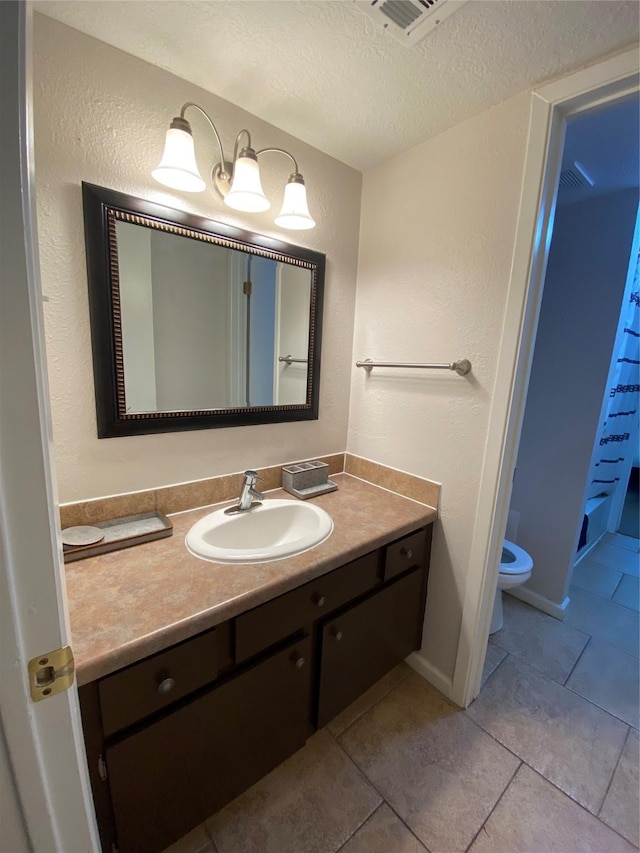 bathroom with vanity, tile patterned floors, toilet, and a textured ceiling