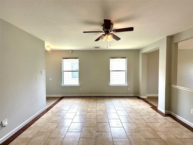 tiled spare room featuring ceiling fan, plenty of natural light, and a textured ceiling