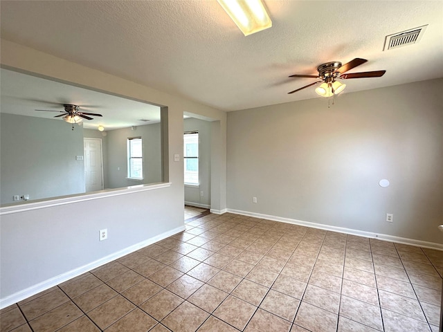 tiled empty room with ceiling fan and a textured ceiling