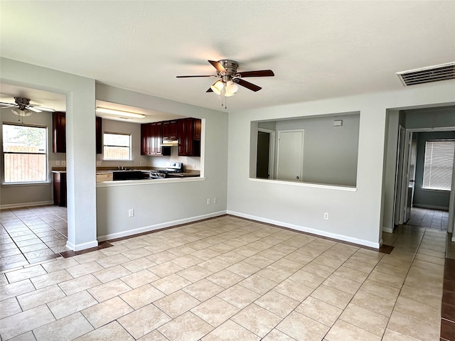 kitchen with light tile patterned floors, stainless steel stove, kitchen peninsula, and ceiling fan