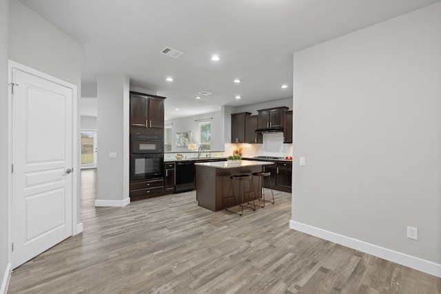 kitchen featuring a kitchen island, a breakfast bar area, dark brown cabinetry, and black appliances