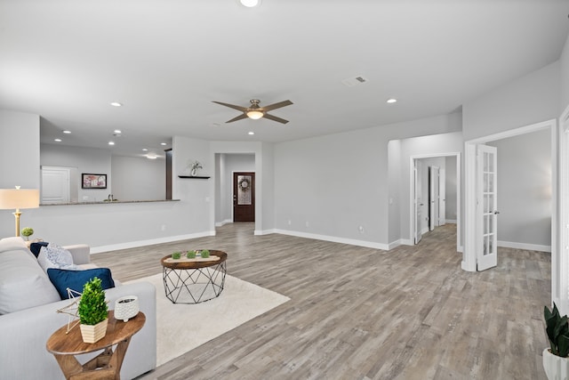 living room with french doors, ceiling fan, and light wood-type flooring