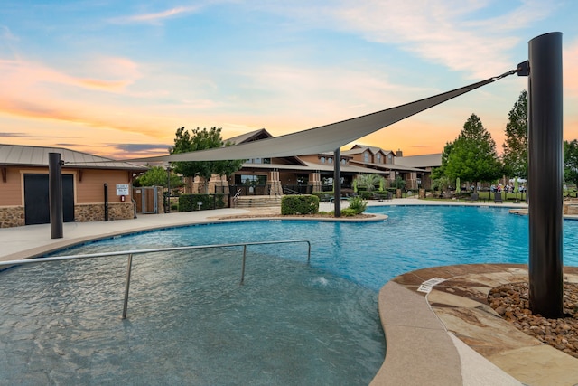 pool at dusk with a patio area