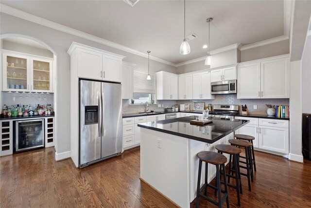 kitchen with a kitchen island, appliances with stainless steel finishes, pendant lighting, white cabinetry, and sink