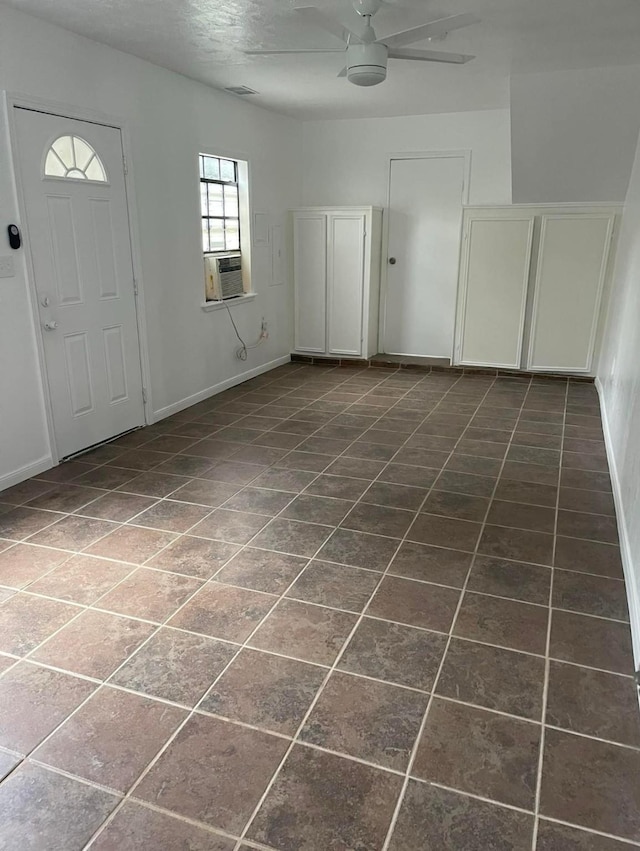 foyer featuring cooling unit, dark tile patterned flooring, and ceiling fan