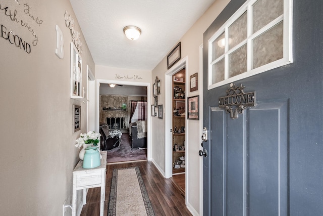 foyer entrance featuring dark wood-style flooring, a fireplace, and a textured ceiling