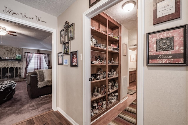 corridor featuring a textured ceiling, baseboards, and wood finished floors