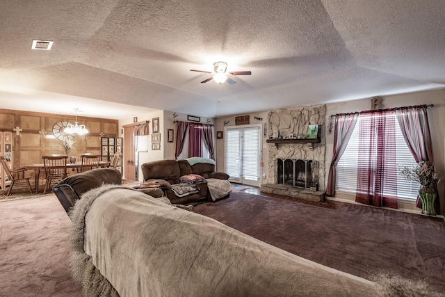 living room with a stone fireplace, visible vents, a ceiling fan, a wealth of natural light, and carpet