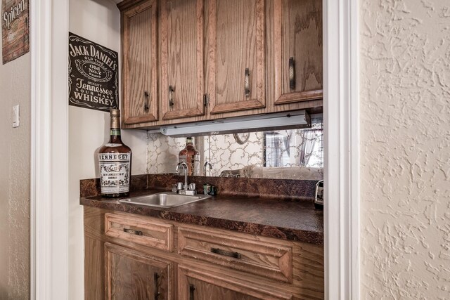 bar with a textured wall, a sink, and wet bar