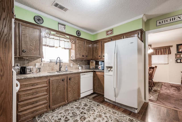 kitchen with sink, dark hardwood / wood-style flooring, decorative backsplash, light stone counters, and white appliances