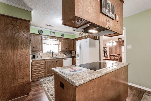 kitchen featuring white appliances, visible vents, dark wood-style flooring, a center island, and a sink