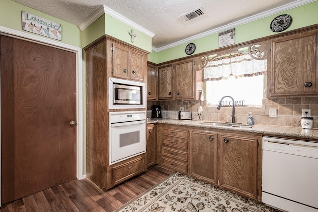 kitchen featuring white appliances, dark hardwood / wood-style floors, sink, and backsplash